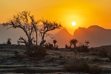 Naklejka na ściany i meble The sun setting over mountains in the desert of Oman.