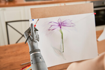 Female artist with prosthesis arm paints on canvas