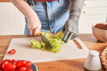 Woman with artificial limb chopping salad with a knife