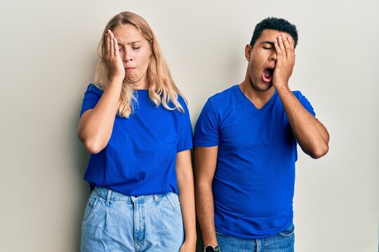 Young interracial couple wearing casual clothes yawning tired covering half face, eye and mouth with hand. face hurts in pain. - Powered by Adobe