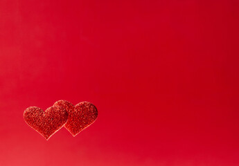 Two red shiny hearts on a red background. The concept of Valentine's day