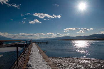 Obraz premium Along the shore of the lake in winter. Plants and reeds covered with snow, boats overturned by the water.