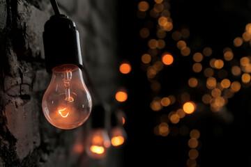 a light bulb against a dark brick wall in the loft style shines with a beautiful orange light....