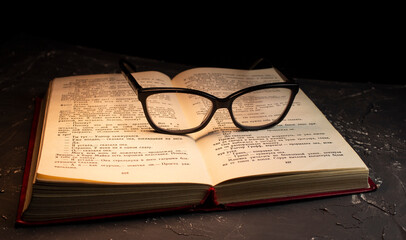 Book and Glasses. Vintage style. Dark background.