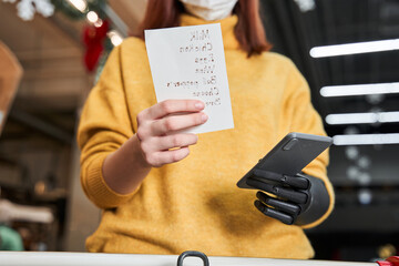 Woman with implant hand buying groceries in store