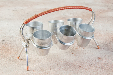 Old aluminum small cups with a stand on concrete background.