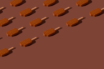 Chocolate popsicles pattern on a brown background. Minimal ice cream layout.