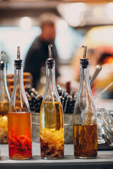 Olive oil in bottle with garlic, red pepper and rosemary on table in pizzeria