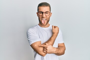 Young caucasian man wearing band aid for vaccine injection sticking tongue out happy with funny expression.