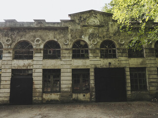 An old abandoned building with cracked walls and peeling plaster, many windows and iron doors
