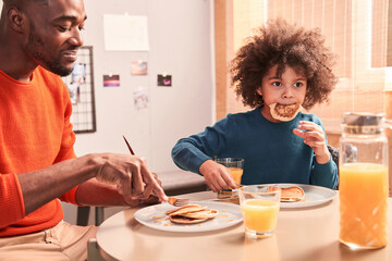 Fototapeta na wymiar Father and son are having tasty breakfast at kitchen