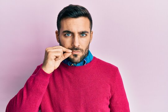 Young hispanic man wearing casual clothes mouth and lips shut as zip with fingers. secret and silent, taboo talking