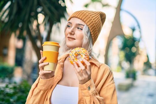 Young blonde girl smiling happy having breakfast at the city.
