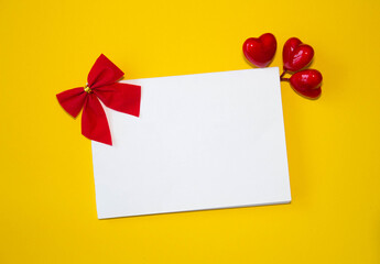 Valentine's day congratulation. Red rose and greeting card with heart sign on yellow background top view copy space