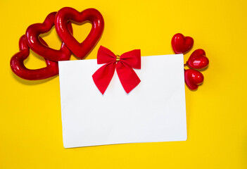 Valentine's day congratulation. Red rose and greeting card with heart sign on yellow background top view copy space