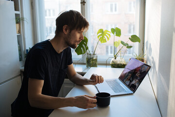 Work at home kitchen. Young man having Zoom video call via a computer in the home office. Stay at...