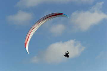 A beautiful view of a paraglide flying gliding on a clear blue sky at the golden hour with a nice wind windy breeze on a sunny day 