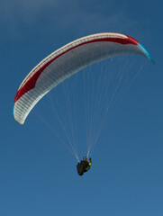 A beautiful view of a paraglide flying gliding on a clear blue sky at the golden hour with a nice wind windy breeze on a sunny day 