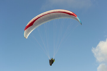 A beautiful view of a paraglide flying gliding on a clear blue sky at the golden hour with a nice wind windy breeze on a sunny day 