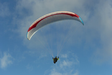 A beautiful view of a paraglide flying gliding on a clear blue sky at the golden hour with a nice wind windy breeze on a sunny day 
