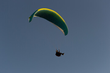 A beautiful view of a paraglide flying gliding on a clear blue sky at the golden hour with a nice wind windy breeze on a sunny day 