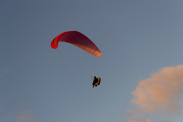 A beautiful view of a paraglide flying gliding on a clear blue sky at the golden hour with a nice wind windy breeze on a sunny day 