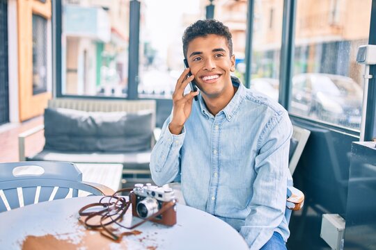 Young latin man smiling happy talking on the smartphone sitting at coffee shop terrace.