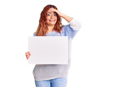 Young latin woman holding blank empty banner stressed and frustrated with hand on head, surprised and angry face