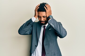 Handsome hispanic man with beard wearing business suit and tie suffering from headache desperate and stressed because pain and migraine. hands on head.
