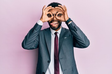 Handsome hispanic business man with beard wearing business suit and tie doing ok gesture like binoculars sticking tongue out, eyes looking through fingers. crazy expression.