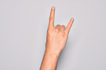 Hand of caucasian young man showing fingers over isolated white background gesturing rock and roll symbol, showing obscene horns gesture