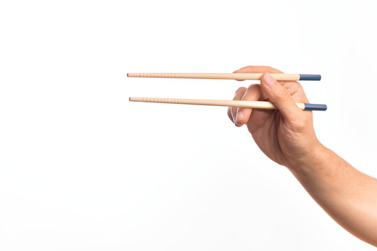 Hand of caucasian young man holding chopsticks over isolated white background