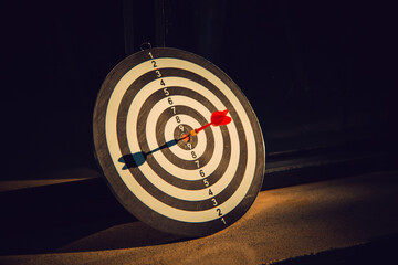 Dart arrow hit on bulleyes of dartboard to represent that the business reached the target  with...