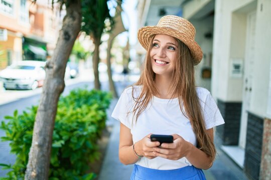 Young blonde woman on vacation smiling happy using smartphone at street of city