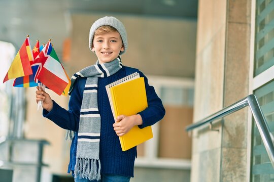 Adorable blond student kid smiling happy holding flags of different countries at the school.