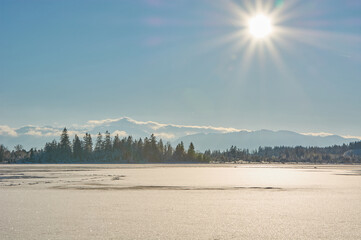 Frozen mountain lake in the sun. Bright sun over a frozen mountain lake in the alps.
