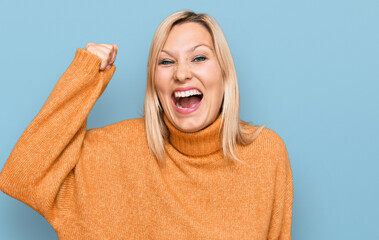 Middle age caucasian woman wearing casual winter sweater angry and mad raising fist frustrated and furious while shouting with anger. rage and aggressive concept.