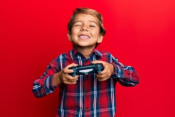 Adorable latin kid playing video game holding controller winking looking at the camera with sexy...