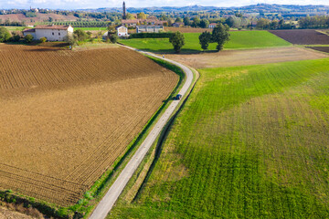 Aerial view of Monferrato countryside, Italian landscape with bright colors. Car passing by a road through the fields. Copy space