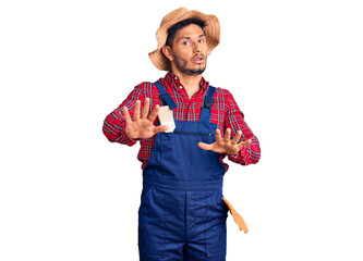 Handsome latin american young man weaing handyman uniform doing stop gesture with hands palms, angry and frustration expression