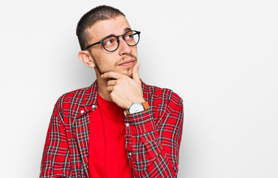 Hispanic young man wearing casual clothes with hand on chin thinking about question, pensive expression. smiling with thoughtful face. doubt concept.