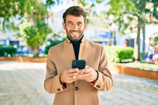 Handsome business man wearing elegant jacket using smartphone smiling happy outdoors