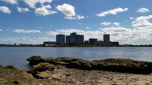 Beautiful video of a river with tall high rise building in the background and blue sky with puffy clouds, Parramatta River, Meadowbank, Sydney, New South Wales, Australia