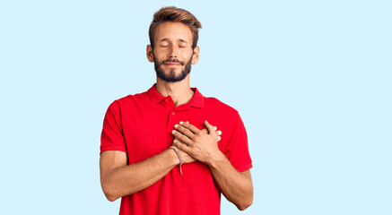 Handsome blond man with beard wearing casual clothes smiling with hands on chest with closed eyes and grateful gesture on face. health concept.