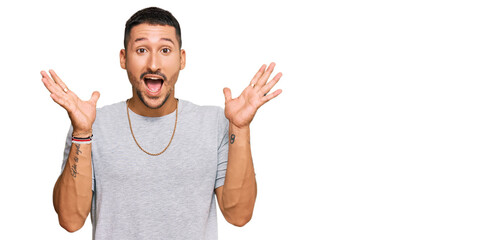 Handsome man with tattoos wearing 90s style celebrating crazy and amazed for success with arms...