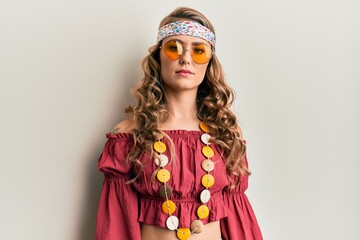 Young blonde girl wearing bohemian and hippie style with serious expression on face. simple and natural looking at the camera.