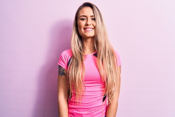 Obraz na płótnie Canvas Young beautiful blonde woman wearing casual t-shirt standing over isolated pink background with a happy and cool smile on face. Lucky person.