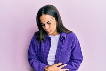 Young brunette woman wearing casual clothes with hand on stomach because indigestion, painful illness feeling unwell. ache concept.