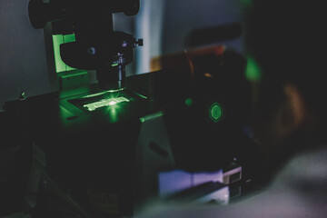 Life science female researcher microscoping with hi-tech fluorescent microscope in scientific...