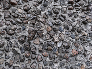 Stone texture of granite stones poured with cement. Decorative wall decoration with granite boulders